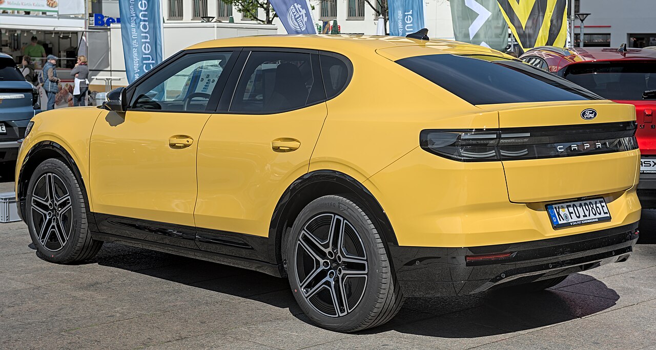 Gelber elektrischer Ford Capri von hinten mit abfallendem Dach und großer Heckklappe.
